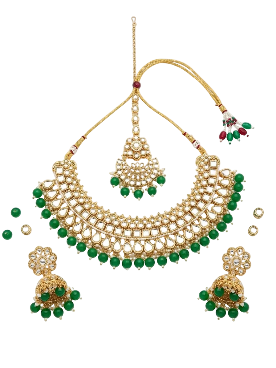 Gold-toned traditional Indian jewelry set featuring a choker necklace, matching dangling earrings, and a maang tikka, embellished with white stones and green beads, displayed on a clean white background.