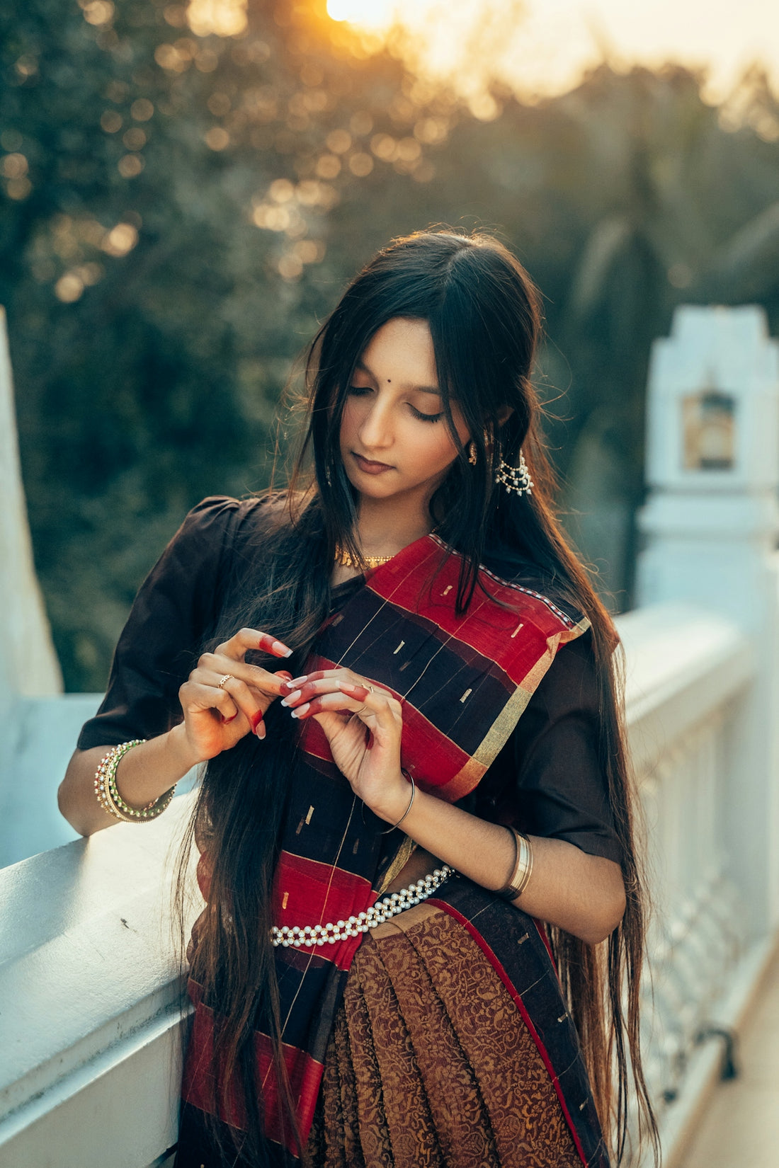 A woman in a sari adjusts her hair outdoors