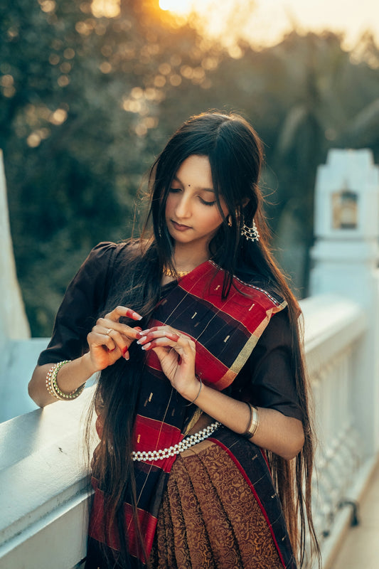A woman in a sari adjusts her hair outdoors