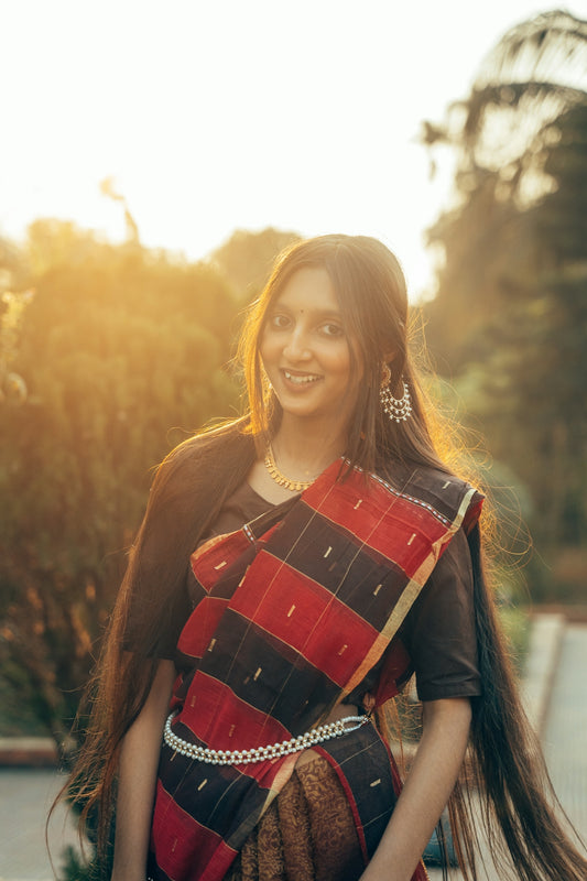 A young woman in a sari smiles in sunlight