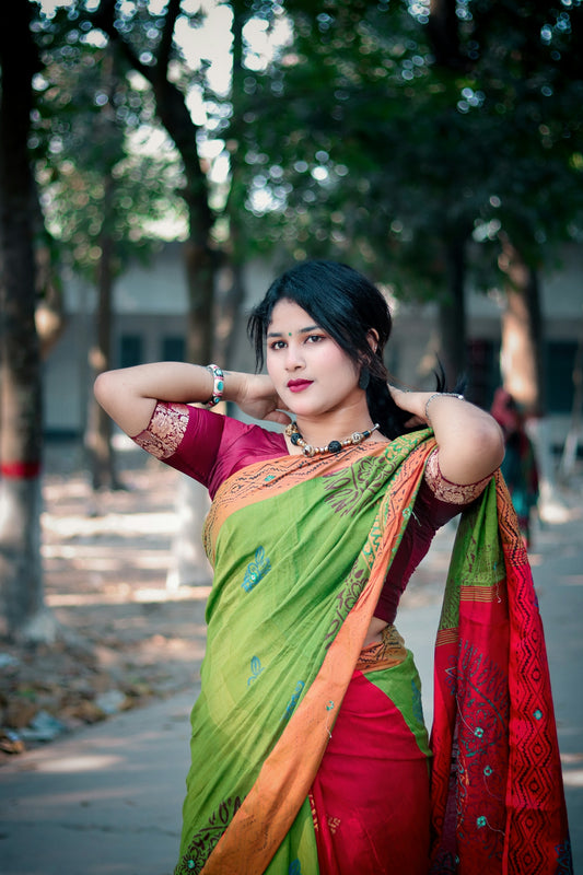 A young woman in a green and red sari outdoors