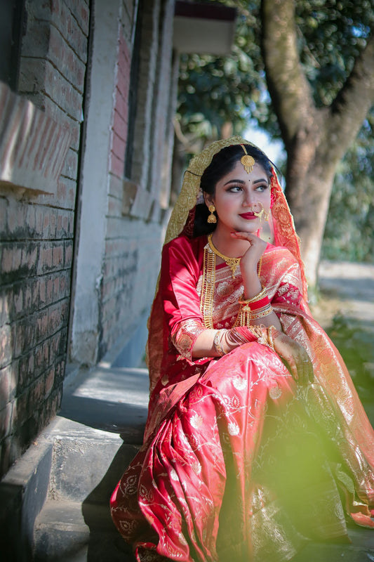 A beautiful woman in a red sari and gold jewelry.