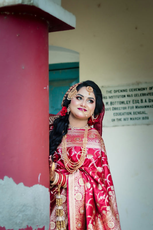 Smiling woman in traditional red and gold bridal attire.