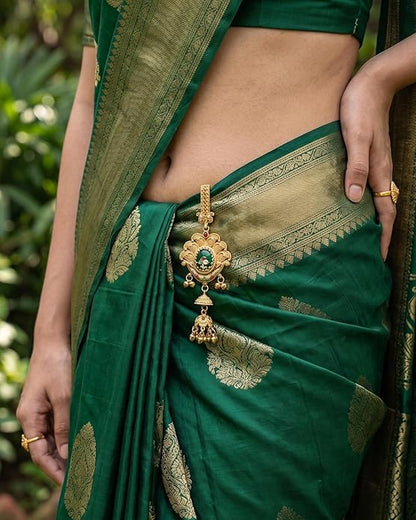 Green saree with gold embroidery and a decorative pendant, worn by a person.