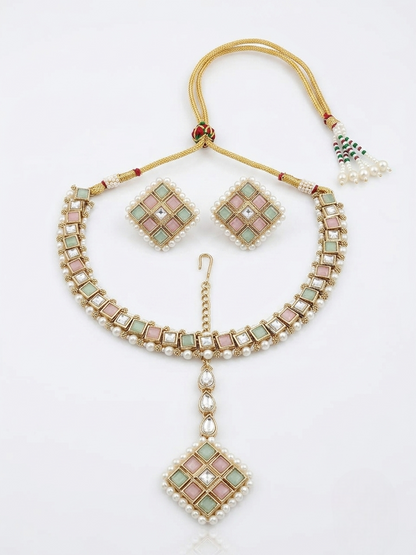 Flat lay display of a pastel pink and green Kundan jewelry set framed with pure white pearls, featuring a choker necklace, matching square earrings, and a central maangtikka on a white background.