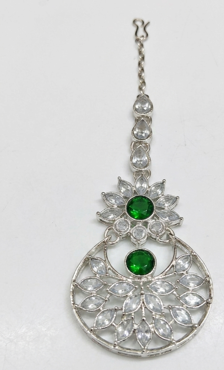 Close-up of silver-tone artificial green stone maang tikka.