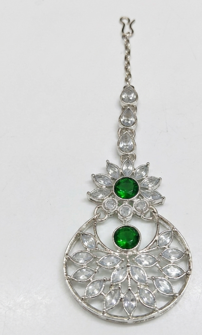 Close-up of silver-tone artificial green stone maang tikka.