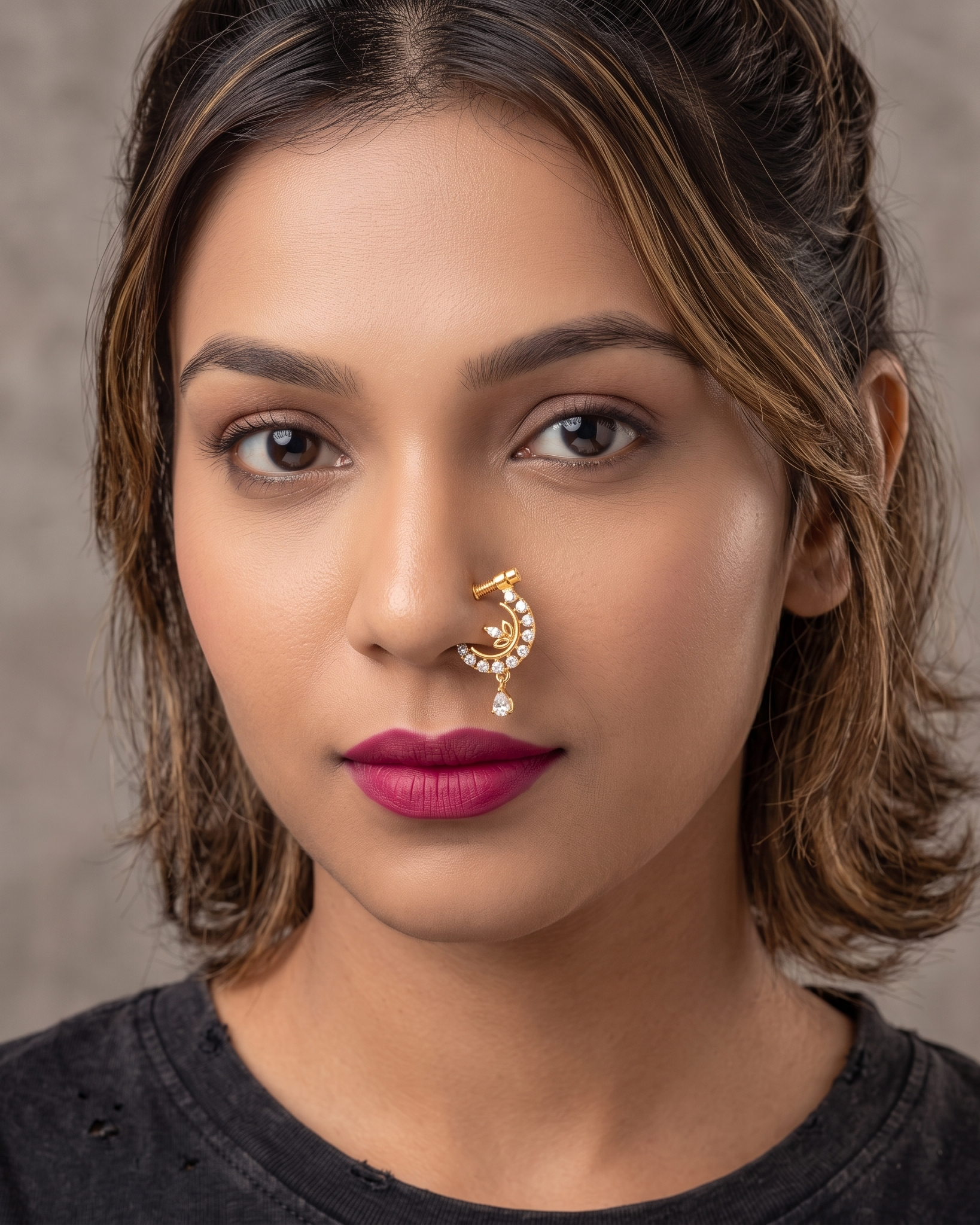 Close-up of a woman with a nose ring and dark lipstick against a neutral background