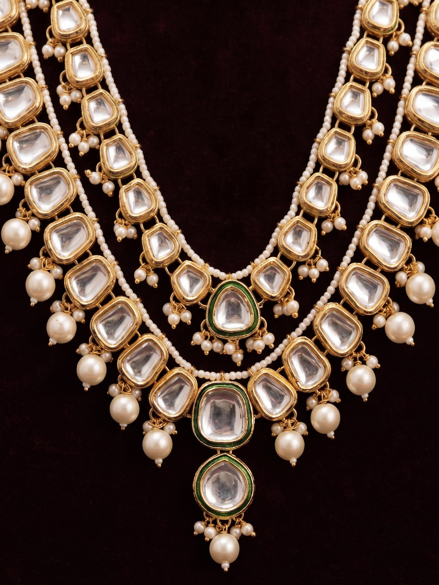 Close-up detail of the imitation clear stones, green enamel trim, and faux pearl tassels on the artificial Kundan jewelry pieces.