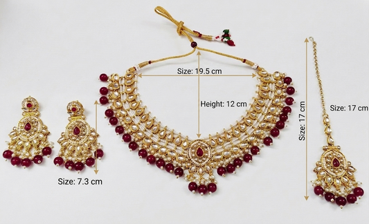 Gold-toned traditional necklace set with matching earrings and maang tikka, decorated with red beads and pearl-like white stones, shown on a white background with size annotations.