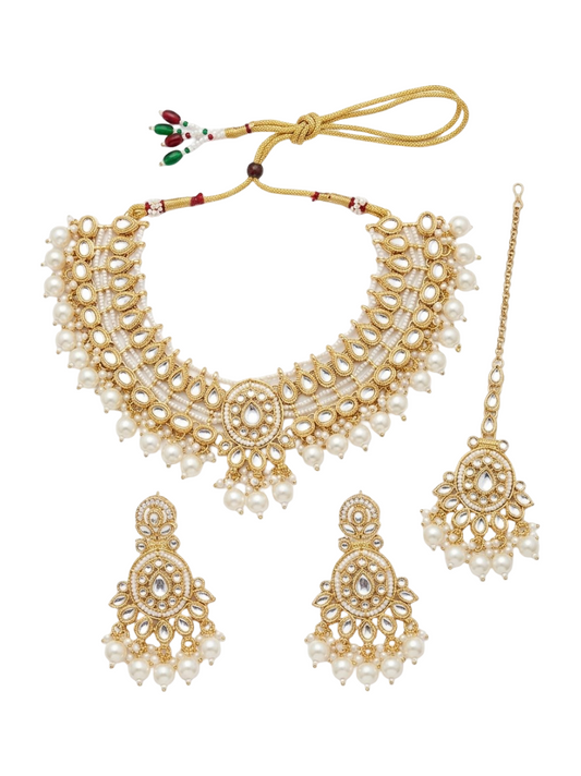 Gold-plated traditional Indian jewelry set featuring a statement necklace, matching earrings, and a maang tikka, embellished with white faux pearls and a central clear stone, on a solid white background.