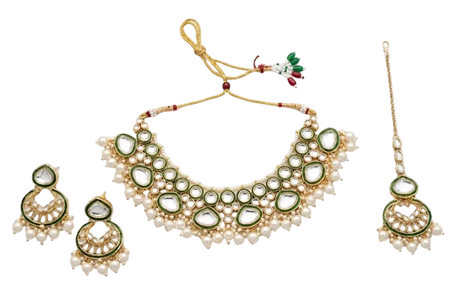 A traditional Indian jewelry set featuring a gold-plated necklace with green enamel and white faux pearls, matching drop earrings, and a maang tikka, displayed on a clean white background.