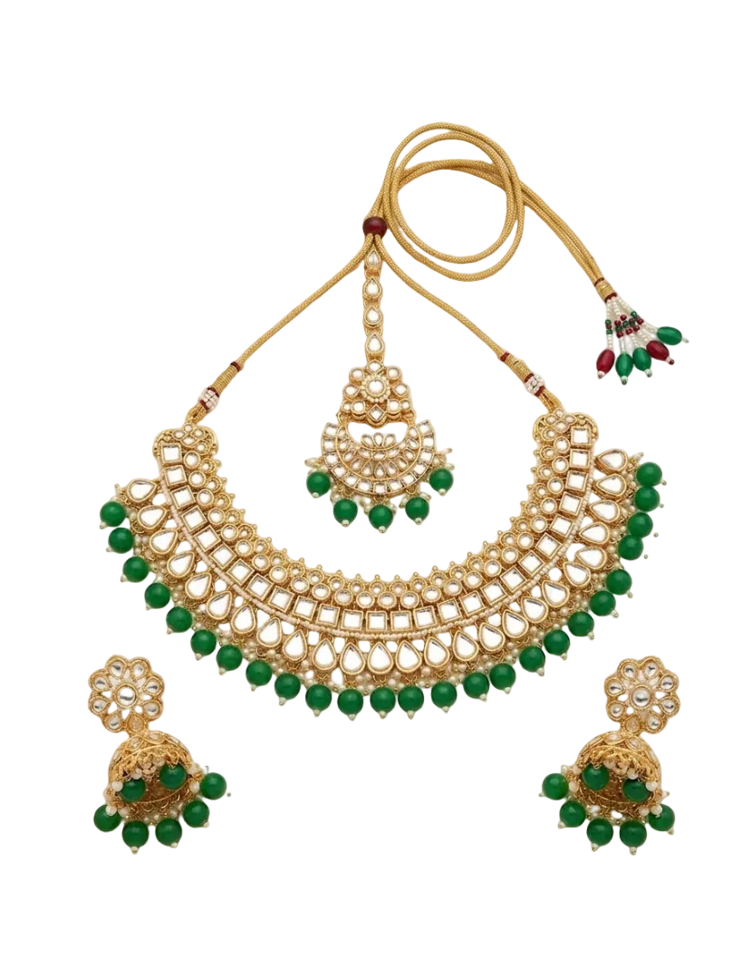 Gold-toned traditional necklace set with a large arched collar necklace, matching pendant, and two jhumka earrings, decorated with green beads and white stones, shown on a plain white background.
