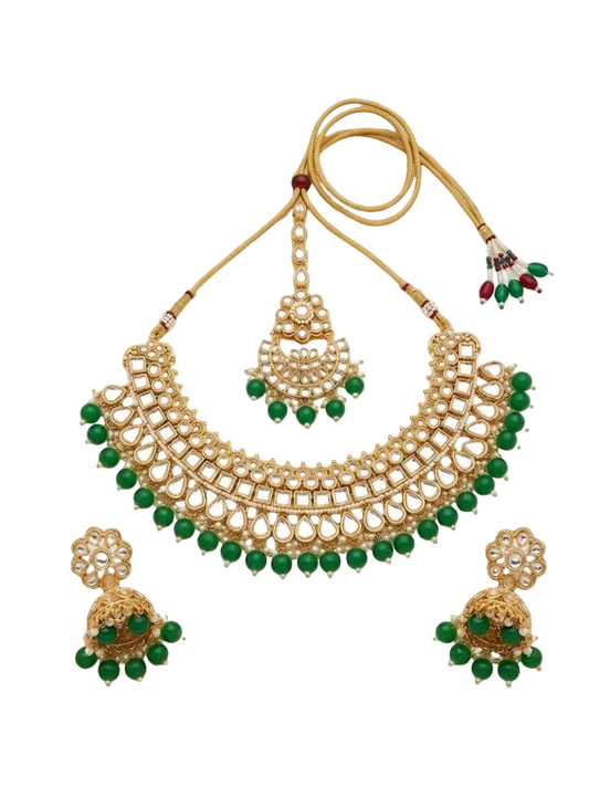 Gold-toned traditional necklace set with a large arched collar necklace, matching pendant, and two jhumka earrings, decorated with green beads and white stones, shown on a plain white background.